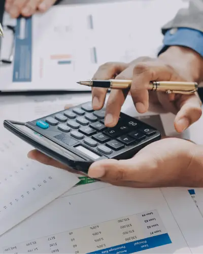 Accountant using a calculator over financial reports