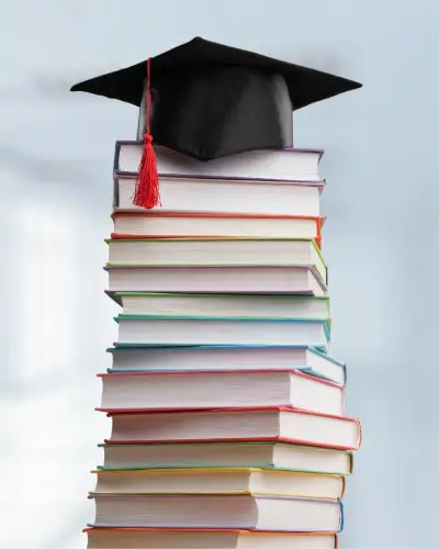 Graduation cap resting on a tall stack of colorful books